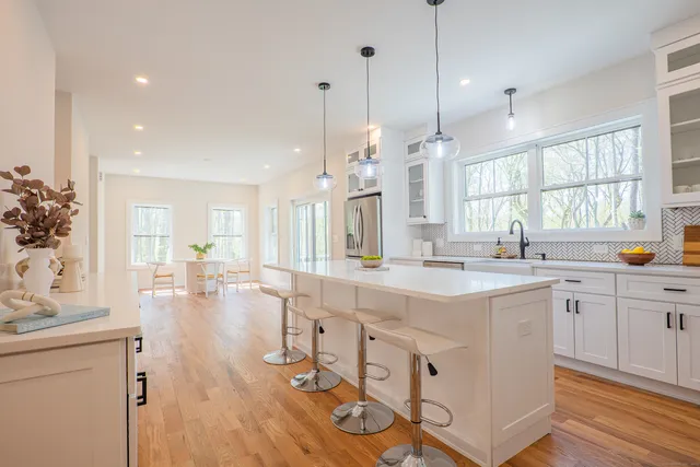 a large kitchen with kitchen island a stove a sink a center island and a wooden floor
