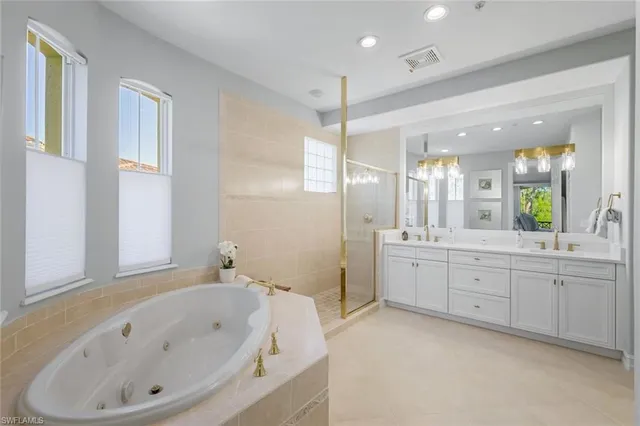 a bathroom with a bathtub a double vanity sink and a large mirror