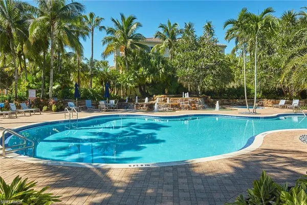 a view of a swimming pool with a lawn chairs and palm trees