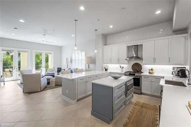 a kitchen with a stove top oven a sink a counter top space and living room view