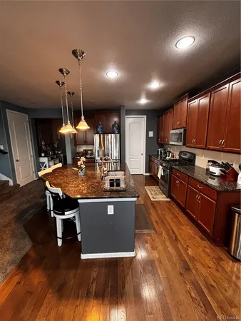 a kitchen with stainless steel appliances granite countertop a sink a stove and a wooden floors