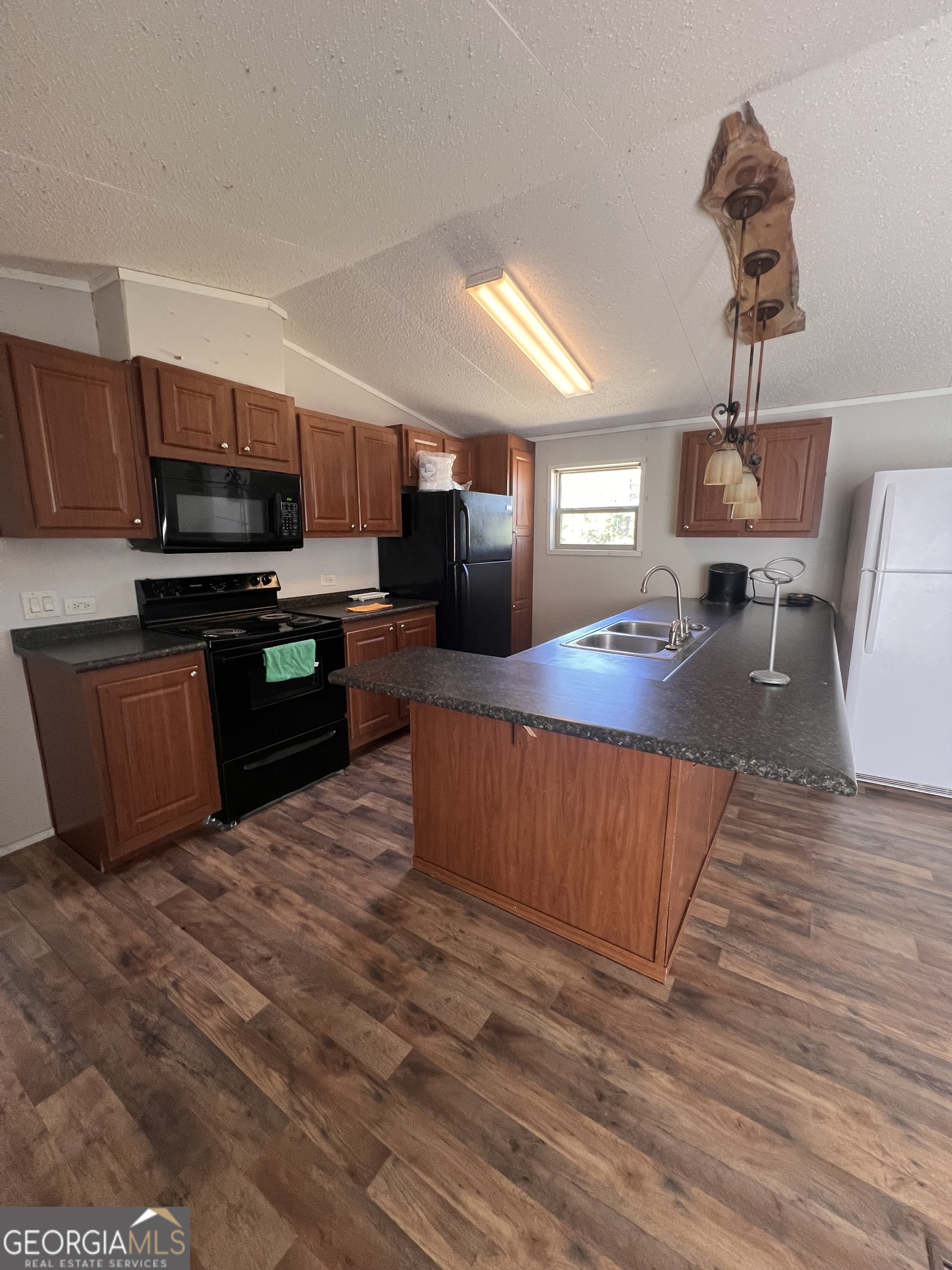 113 Riverview Soperton, GA 30457 - Photo 5 of 16 a kitchen with stainless steel appliances wooden floors wooden cabinets a refrigerator and microwave
