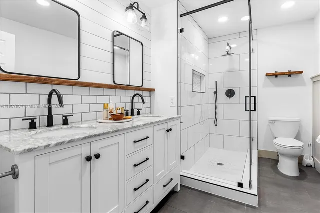 a bathroom with a granite countertop sink a toilet and shower