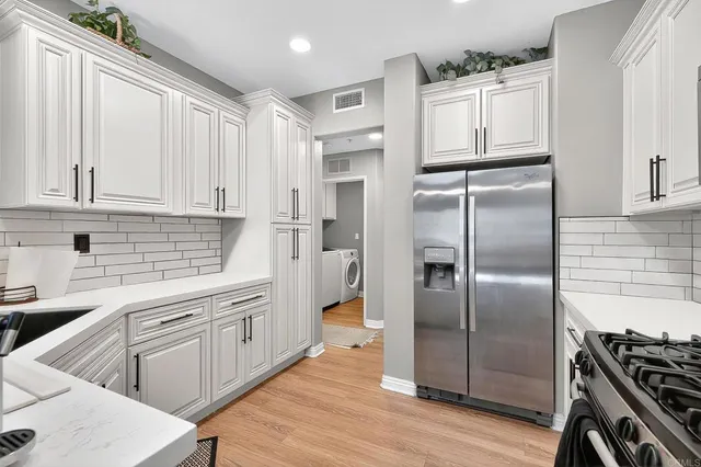 a kitchen with white cabinets and stainless steel appliances