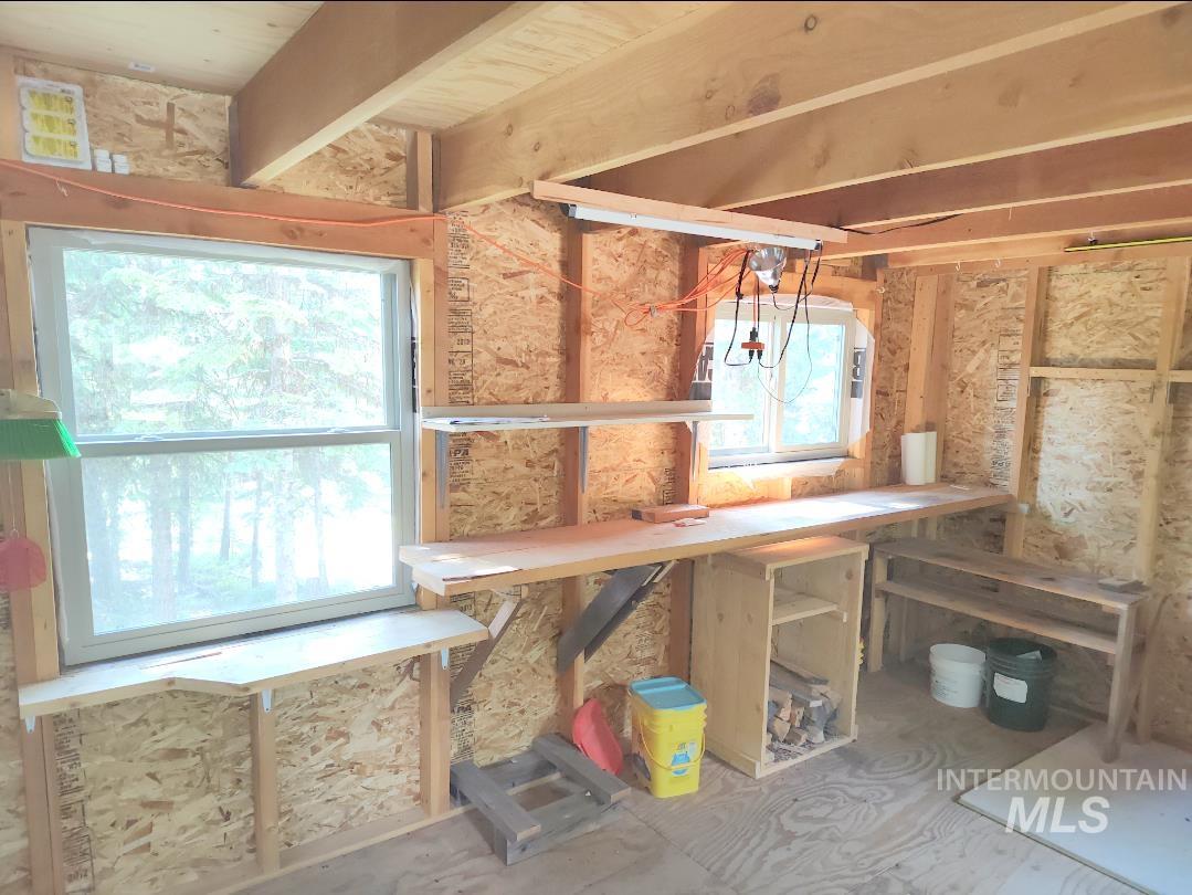 524 Rhett Creek Road Elk City, ID 83525 - Photo 10 of 23 Exposed wood ceiling beams, two windows providing natural illumination, built-in shelving, and a long built-in workbench