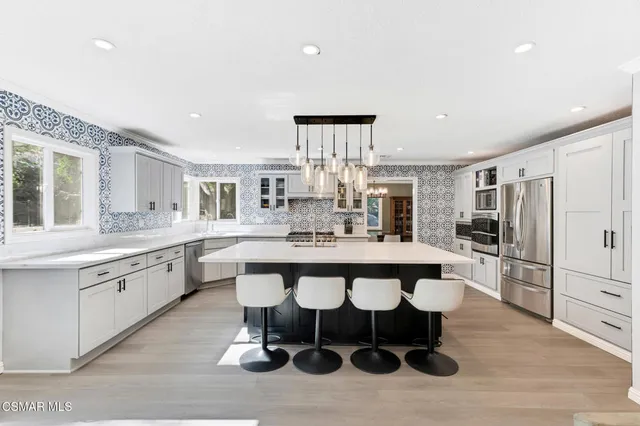 a large kitchen with stainless steel appliances a large counter top a sink dishwasher and a stove with wooden floor