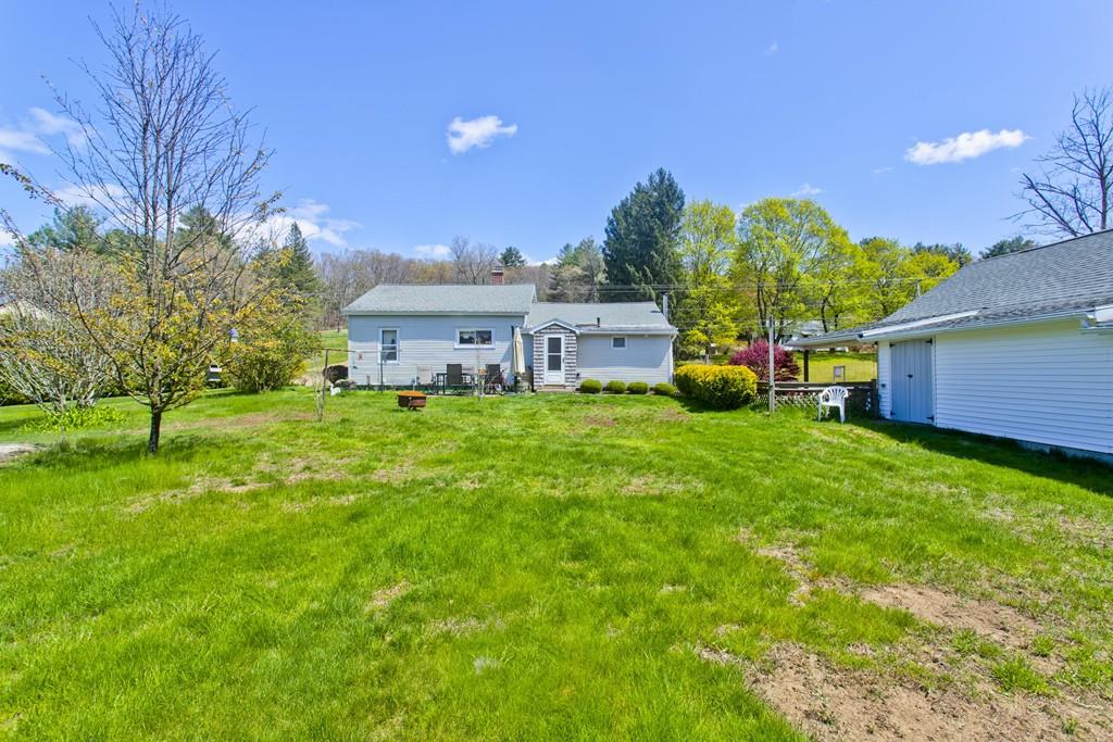 401 Palmer Road Ware, MA 01082 - Photo 10 of 34 a view of a house with a big yard potted plants and a large tree