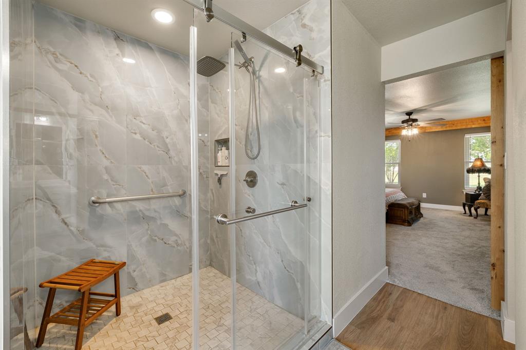 12240 Wellington Road Ponder, TX 76259 - Photo 24 of 40 Walk-in shower featuring large-format marble-look wall tiles, a rain shower head, and a hand-held shower fixture