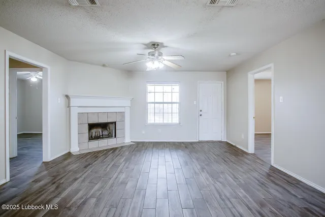 an empty room with wooden floor fireplace and windows