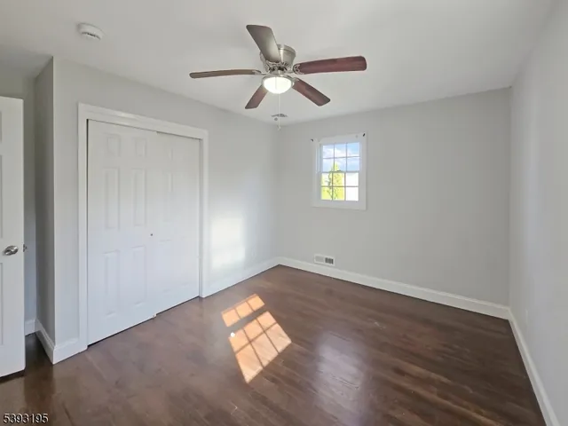 an empty room with wooden floor chandelier fan and windows
