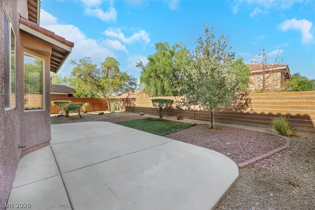 10328 Hawk Ravine Street Las Vegas, NV 89178 - Photo 47 of 55 A spacious backyard with mature trees and a broad concrete patio for outdoor enjoyment.