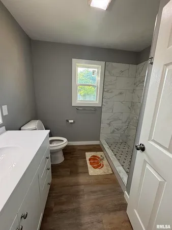 a bathroom with a sink a toilet a window and shower