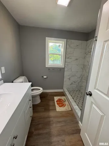 a bathroom with a sink a toilet a window and shower