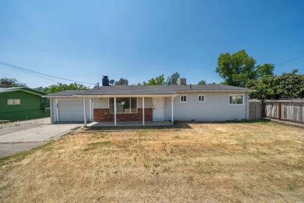 a view of a house with a yard and a large tree