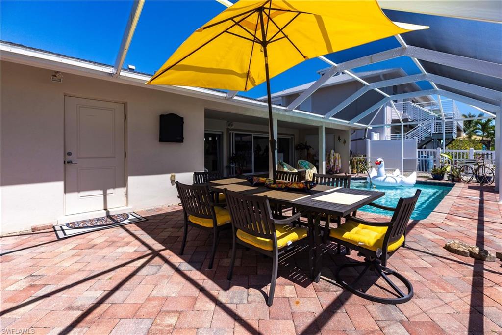 164 Trinidad Street Naples, FL 34113 - Photo 11 of 43 a view of a patio with table and chairs under an umbrella
