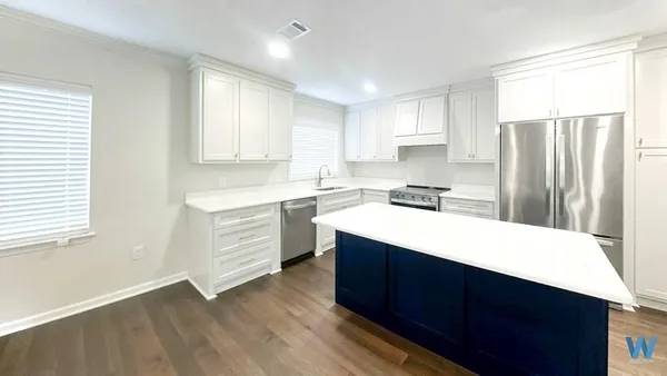 a kitchen with a sink a stove a refrigerator and white cabinets