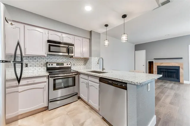 a kitchen with stainless steel appliances granite countertop a stove top oven a sink and a microwave