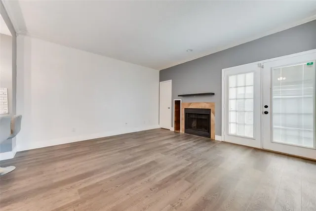 an empty room with wooden floor fireplace and windows
