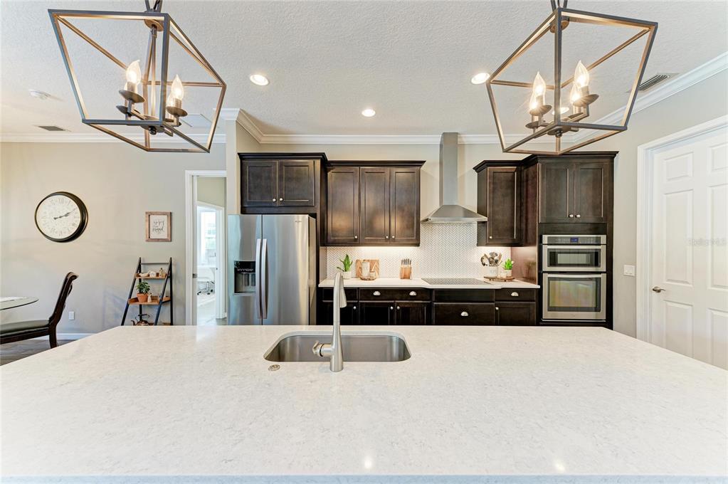 16336 26th Street East Parrish, FL 34219 - Photo 21 of 69 a kitchen with stainless steel appliances granite countertop a refrigerator a sink dishwasher a stove and a dining table with wooden floor