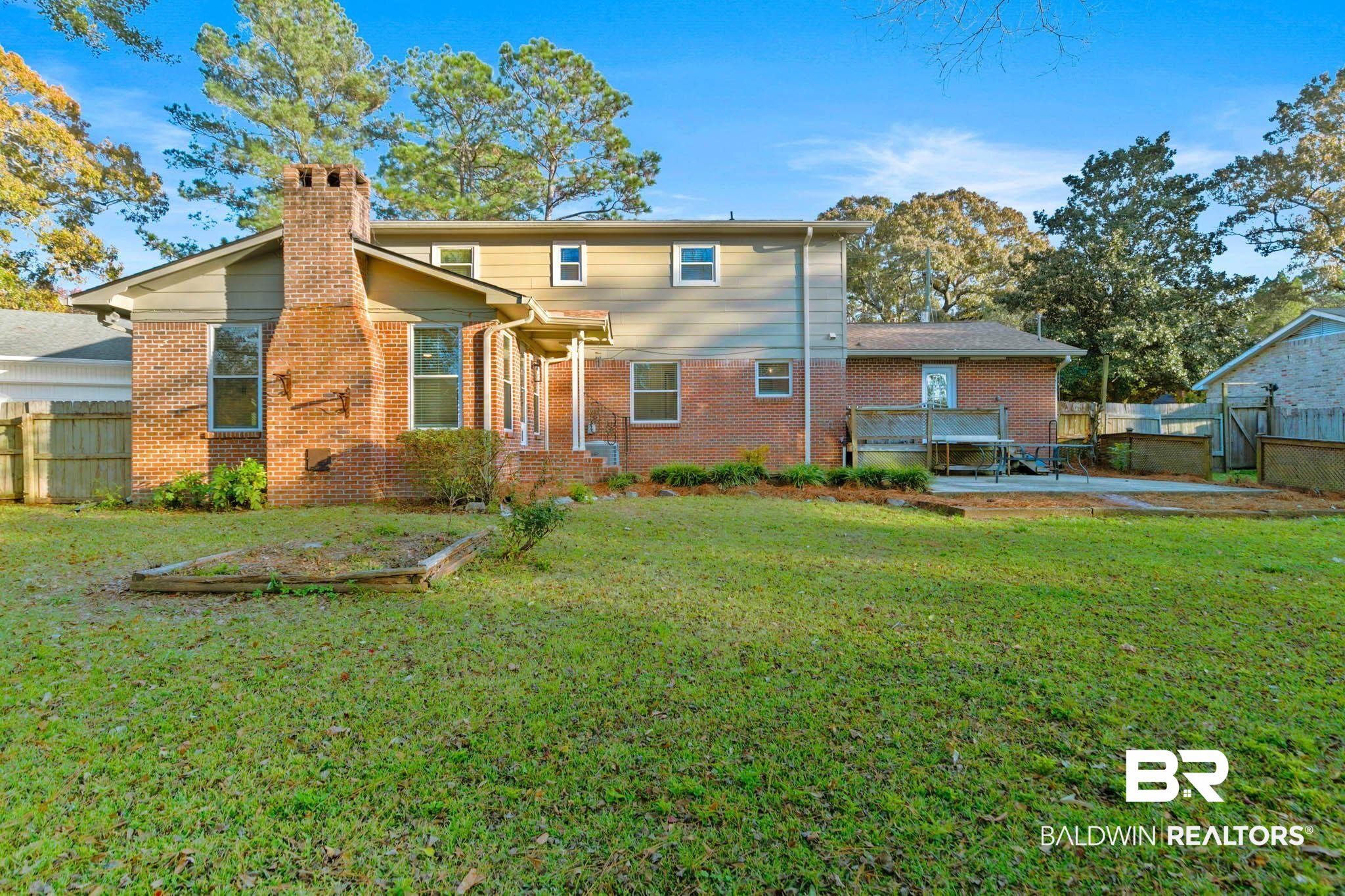 608 Southern Way Daphne, AL 36527 - Photo 32 of 35 Back of house featuring a fenced backyard, brick siding, and a chimney