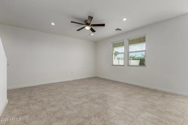 an empty room with windows and ceiling fan