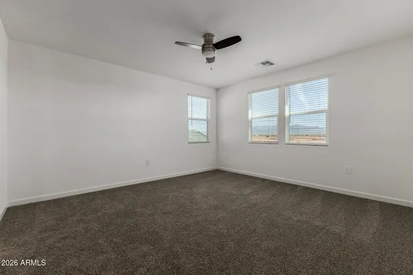 an empty room with ceiling fan and windows