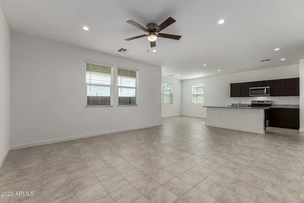 a view of an empty room with a window and a kitchen