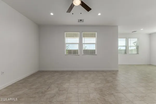 an empty room with chandelier fan and windows