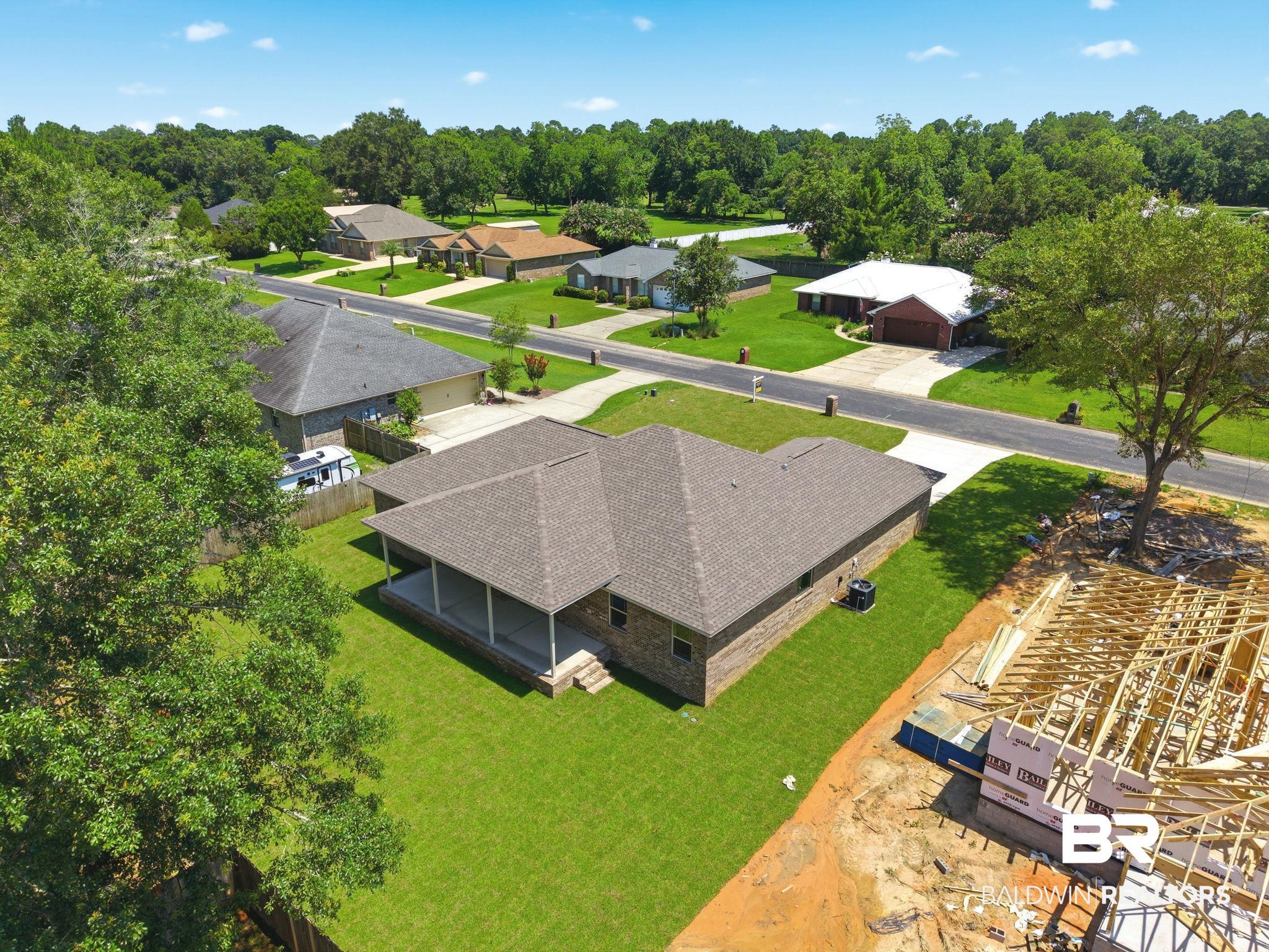 32656 Arbor Ridge Circle Lillian, AL 36549 - Photo 42 of 56 Single-story brick exterior home featuring a covered back patio, a shingle roof, and a meticulously maintained lawn