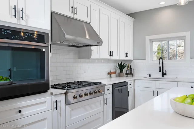 a kitchen with stainless steel appliances a stove a white cabinets and a potted plant