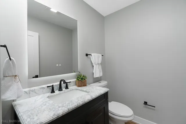 a bathroom with a granite countertop sink a toilet and mirror
