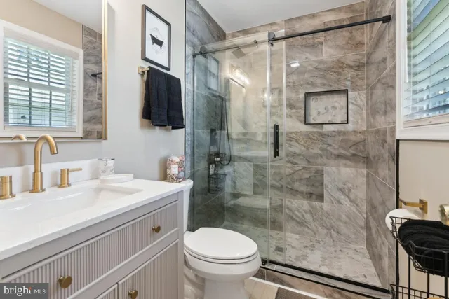 a bathroom with a granite countertop sink toilet a mirror and shower