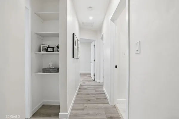 a view of a hallway with wooden floor and a bathroom