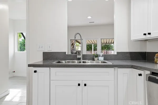 a sink with a granite countertop cabinets and a window