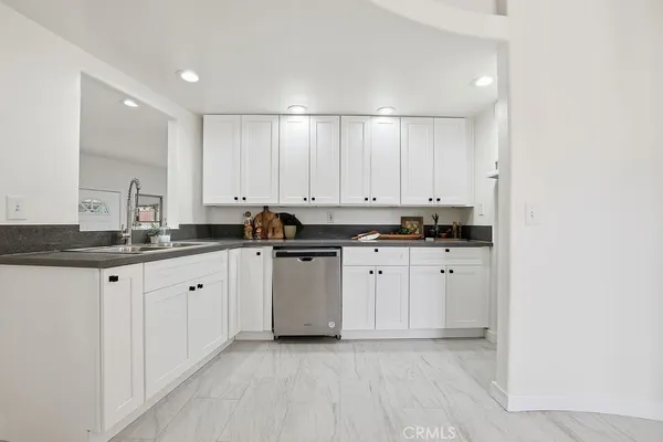 a kitchen with granite countertop white cabinets and black appliances