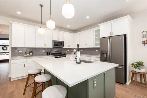 a kitchen with stainless steel appliances a stove a sink a refrigerator cabinets and a dining table