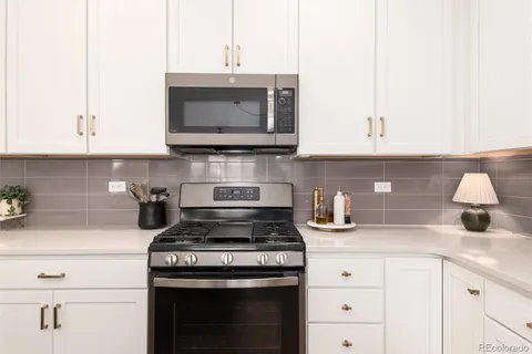 a kitchen with stainless steel appliances granite countertop white cabinets a stove a sink and dishwasher