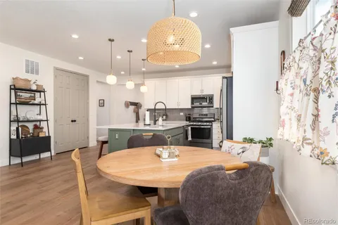 a kitchen with stainless steel appliances kitchen island granite countertop a table chairs and a refrigerator
