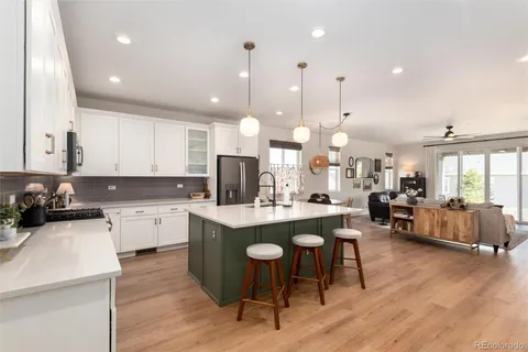 a kitchen with stainless steel appliances kitchen island granite countertop a stove a sink a refrigerator and white cabinets with wooden floor