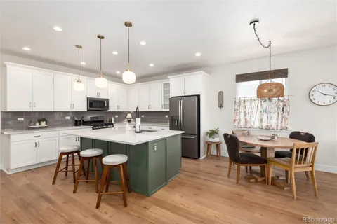 a kitchen with stainless steel appliances kitchen island granite countertop a table chairs and a refrigerator