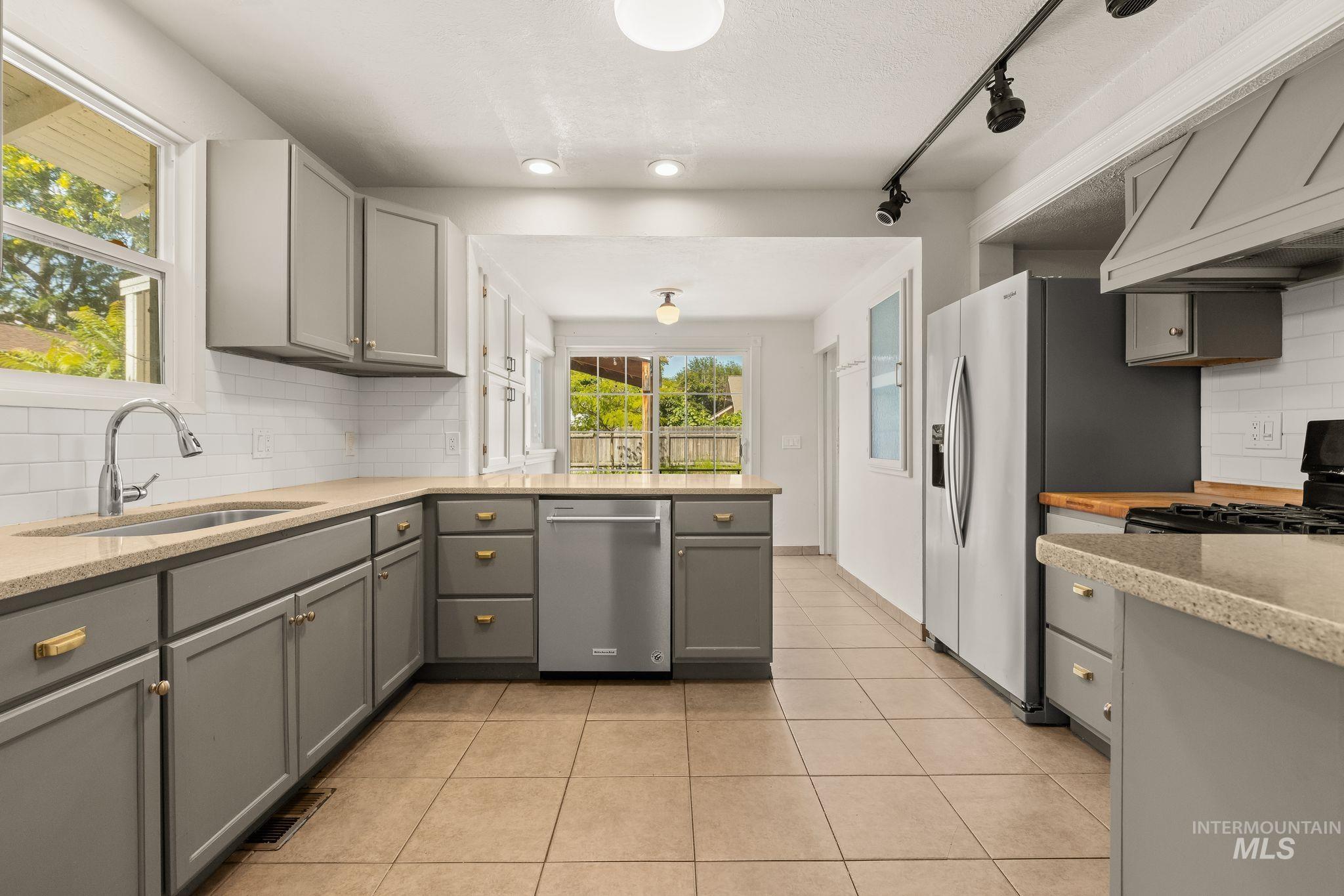 928 3rd Street Clarkston, WA 99403 - Photo 10 of 44 Kitchen featuring gray shaker-style cabinetry with gold-tone hardware, granite-finish countertops, and a subway tile backsplash