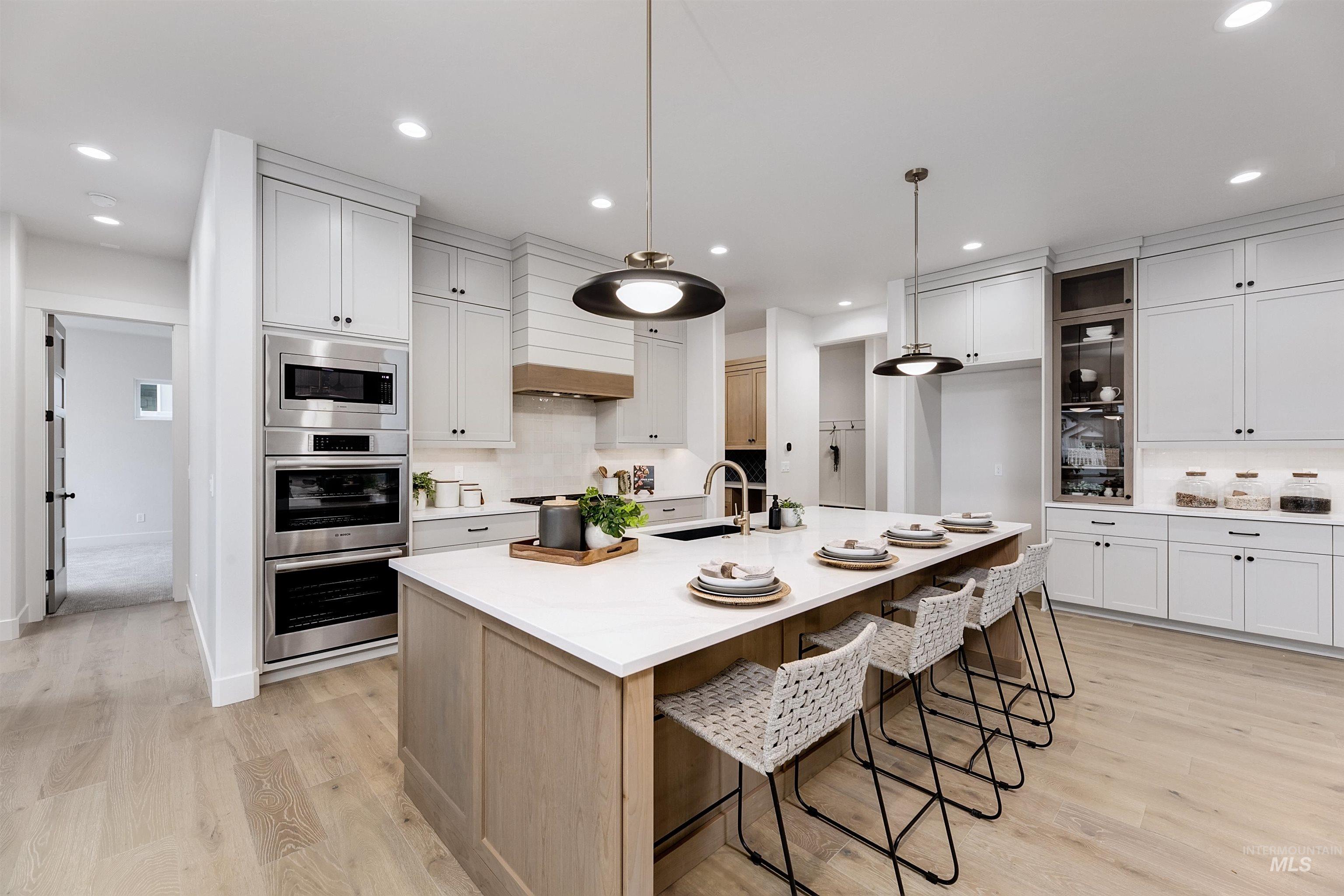 13331 North Spring Creek Way Boise, ID 83714 - Photo 12 of 43 Kitchen featuring backsplash, a kitchen bar, stainless steel appliances, a center island with sink, and two tone cabinetry