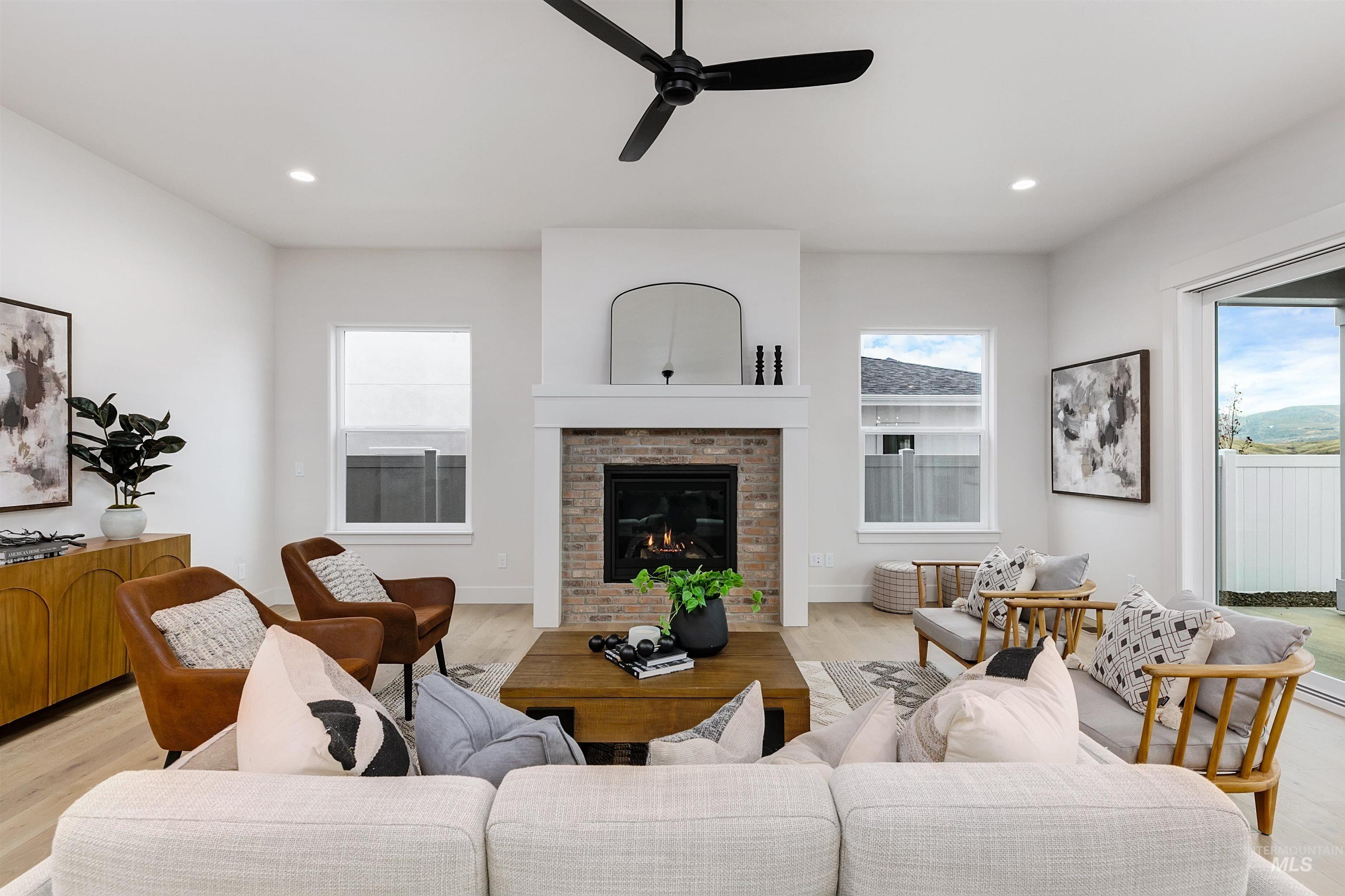 13331 North Spring Creek Way Boise, ID 83714 - Photo 3 of 43 Living area with light wood-style flooring, a ceiling fan, a brick fireplace, healthy amount of natural light, and recessed lighting