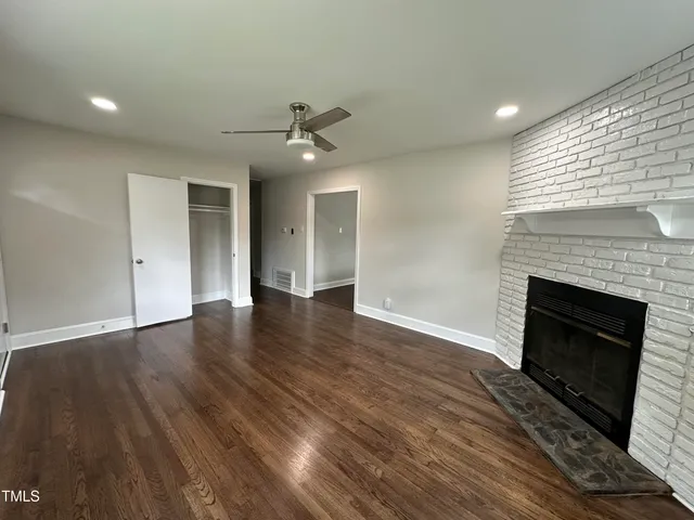 a view of empty room with wooden floor and fireplace