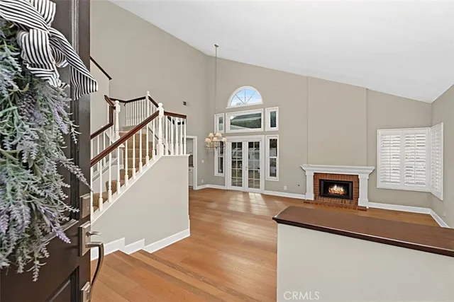 a view of an empty room with wooden floor fireplace and a window