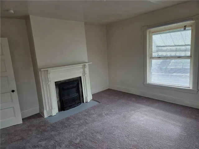 an empty room with a fireplace and window