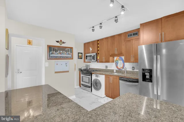 a kitchen with stainless steel appliances granite countertop a refrigerator and a stove top oven