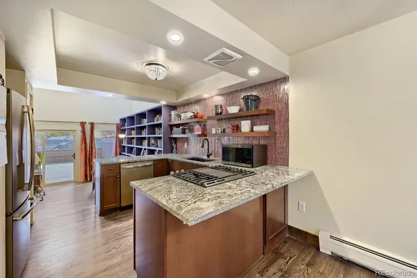 a open kitchen with stainless steel appliances granite countertop a stove and a wooden floors