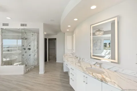 a bathroom with a granite countertop double vanity sink a mirror and a shower