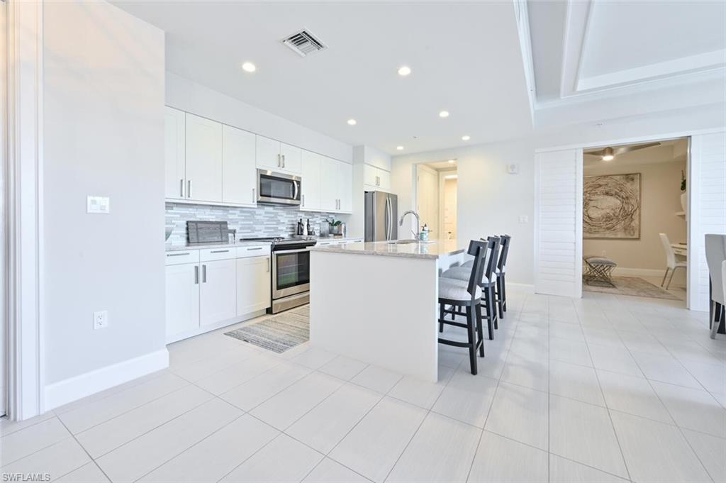 1111 Central Avenue, Unit 303 Naples, FL 34102 - Photo 12 of 50 a kitchen with a cabinets and chairs in it